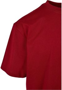 T-shirt en coton rouge uni à manches courtes avec col rond, vu depuis le haut côté avant gauche.