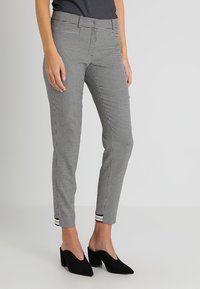 Svart och vit houndstooth-mönstrade byxor med slim fit, med platt framdel, sidofickor och manschettslut. Tillsammans med svarta klackar.