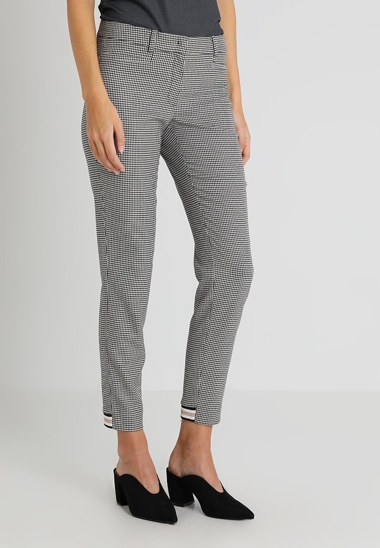 Svart och vit houndstooth-mönstrade byxor med slim fit, med platt framdel, sidofickor och manschettslut. Tillsammans med svarta klackar.