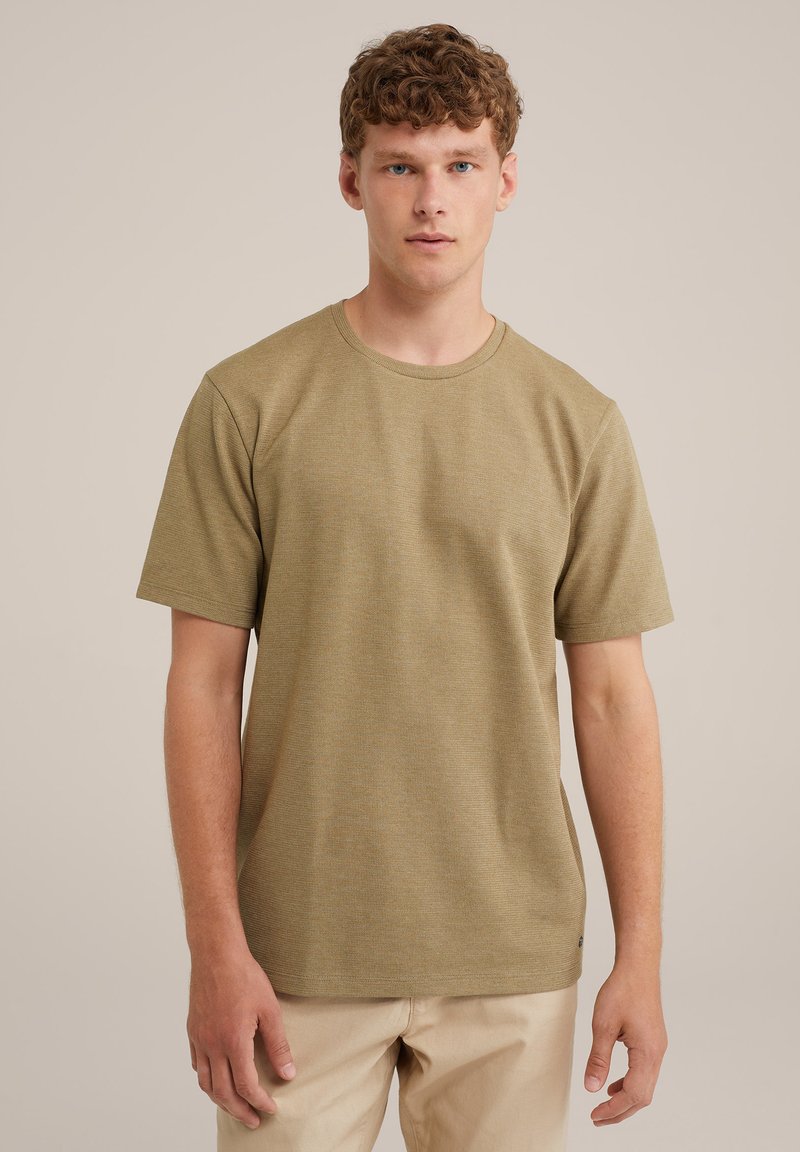 Camiseta de manga corta color verde oliva con escote redondo, tela texturizada y corte relajado. Combinada con pantalones beige claros.