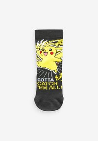 Czarne skarpetki z żółtym wzorem Pikachu, czerwonymi policzkami i hasłem "Musisz je złapać wszystkie" w pogrubionym żółtym tekście.