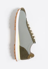 Zapatillas de tela gris y ante oliva con una mediasuela blanca, acentos de color amarillo claro y cordones en crema. Suela texturizada con patrones de tracción.