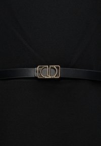 Ceinture en cuir noir dotée d'une boucle double "C" en métal doré avec une finition texturée. Design élégant et minimaliste, adapté à diverses tenues.
