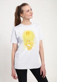 Bílý bavlněný tričko s žlutým grafickým designem slunce a hravého medvěda. Kulatý výstřih, krátké rukávy, volný střih.