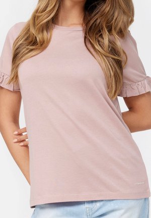 Jasnoróżowy T-shirt z krótkim rękawem z falbankami, dekoltem typu crew oraz luźnym krojem. Tkanina wydaje się miękka i gładka.