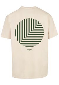Beige cotton t-shirt featuring a circular green striped graphic on the back. The design includes various horizontal and vertical lines.
