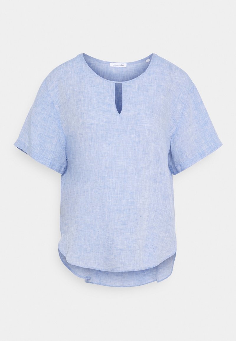 Blouse en lin bleu clair à manches courtes, col rond, petite fente devant et ourlet légèrement arrondi, présentée sur fond uni.