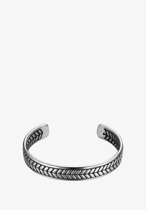 Ródiumozott ezüst karkötő, középen kiemelkedő chevron mintával, fényes felülettel és sima, lekerekített élekkel.