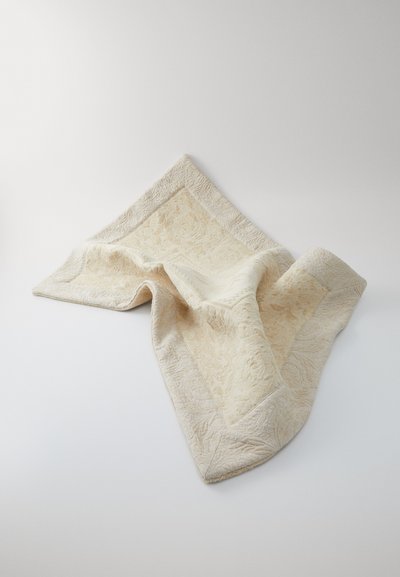 Textured cream blanket with a patterned surface and contrasting stitched edges, draped in a diagonal position on a light background.