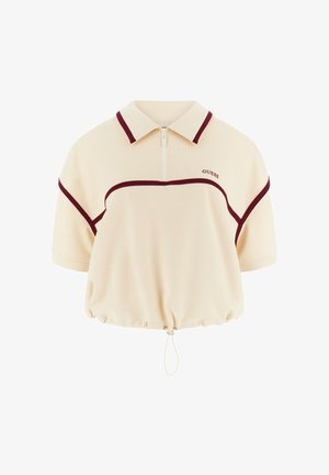 Polo corta beige con rifiniture color marrone scuro, maniche corte, cerniera frontale, orlo con coulisse e logo "GUESS" sul petto.