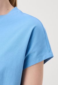 Ljusblå kortärmad t-shirt i bomull. Rund halsdesign med en slät textur och sydda fållar. Enkelt och utan mönster.