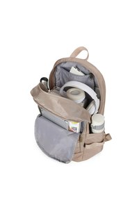 Sac à dos beige avec plusieurs compartiments. L'intérieur présente une doublure grise, une pochette pour ordinateur portable, des écouteurs et un porte-bouteille cylindrique.