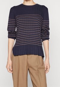 Granatowy sweter z prążkowanego dzianinowego materiału z poziomymi beżowymi paskami, okrągłym dekoltem i podwiniętymi rękawami. Nieco dłuższy tylny dół z bocznymi rozcięciami.