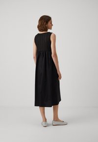 Crna haljina bez rukava s teksturiranim pletenim gornjim dijelom i lepršavom suknjom. Uparena s srebrnim ravnim cipelama. Simple i elegantan dizajn.