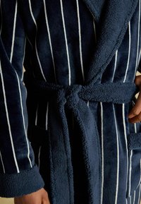 Navyblå morgonrock med vita vertikala ränder, tillverkad av mjuk sammet. Har ett bälte och en ficka, accentuerad med en plyschkrage.