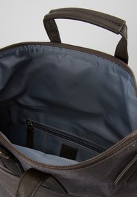 Bolsa de tela de color gris oscuro con asas de cuero suave, cierre con cremallera y un interior forrado. Cuenta con un pequeño bolsillo con cremallera en el interior.