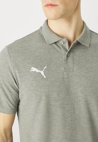 Šedé bavlněné polo tričko s límečkem, dvěma knoflíky a bílým logem Puma na levé straně. Hladký povrch a neformální design.