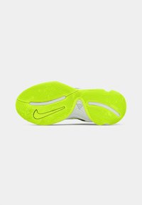 Lyst grøn-gul sål på en Nike-sko med strukturerede grebmønstre, hvide accenter og Nike swoosh-logo synligt på en hvid baggrund.