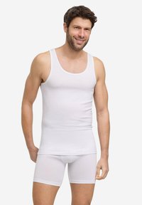 Set di canotta bianca e boxer. Tessuto di cotone liscio e aderente. La canotta ha spalline larghe; i pantaloni corti hanno una lunghezza a metà coscia e una cintura elastica.