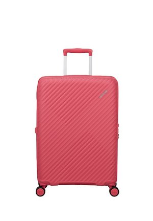 Valigia rigida rossa con scanalature diagonali, manico telescopico, quattro ruote e piccolo logo nell'angolo in alto a destra.