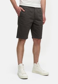 Shorts en coton gris foncé avec poches latérales, une ceinture simple et une coupe droite, portés avec des baskets montantes blanches.