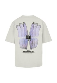 Lys grå t-shirt med et stort lilla sommerfuglegrafik på ryggen, med sort tekst nedenfor, der står "METAMORFOSES HISTORIE."