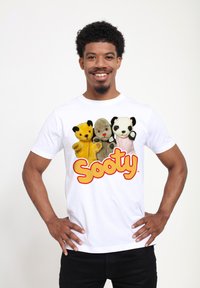 Hvid t-shirt med plysdyrdesignet: en gul bjørn, en grå bjørn og en sort-hvid panda, med "Sooty" tekst i orange nedenfor.