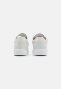 Hvite skinnsneakers med en jevn tekstur, med lavt snitt og diskret merkevarenavn på hælen og sålen. Gummiyttersåle.