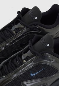 Paire de chaussures de course Nike noires avec des empiècements en mesh et synthétiques, lacets noirs et logo Nike swoosh sur le côté et la languette.