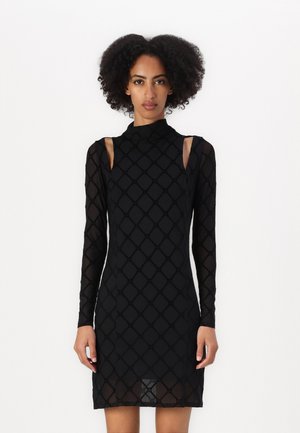 Abito nero a maniche lunghe con motivo a diamante, collo alto e design con spalle scoperte. Realizzato in un tessuto trasparente e testurizzato. Lunghezza a metà coscia.