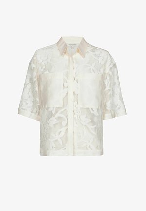 Blouse crème à manches courtes avec motif en dentelle florale, col en satin, deux poches avant unies, style boutonné.