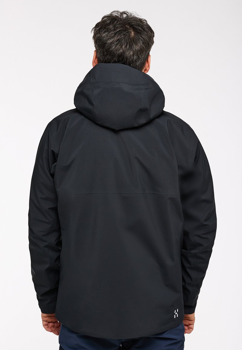 Veste noire imperméable avec capuche, au design épuré, texture lisse et poignets ajustables. Marque discrète au bas.