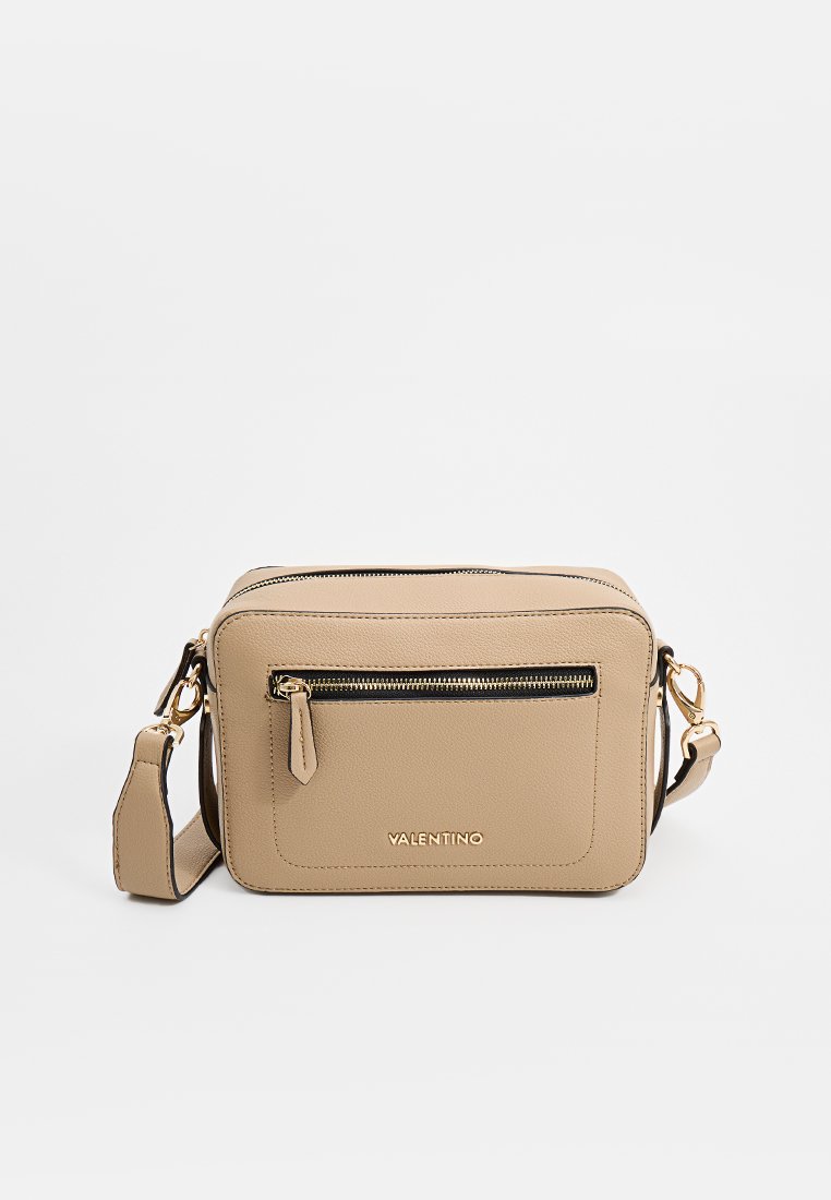 Beige Leder Crossbody-Tasche mit einer vorderen Reißverschlusstasche, goldenen Beschlägen, verstellbarem Tragegurt und geprägtem Markennamen an der Unterseite.