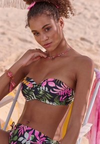 Juodas bikini kostiumas su rožiniais ir žaliais tropiniais lapų raštais; be petnešėlių viršus su susiraukšlėjimu, kartu su atitinkamais bikini apatiniais.