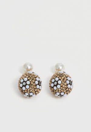 Boucles d’oreilles clous rondes avec dessus en perle, ornées de strass dorés et de motifs floraux blancs sur des bases sphériques foncées.