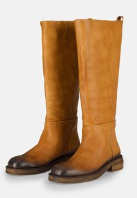 Botas de cuero hasta la rodilla en tono marrón claro con un acabado suave, puntera color marrón oscuro y un robusto tacón de madera. Diseño minimalista sin herrajes visibles.