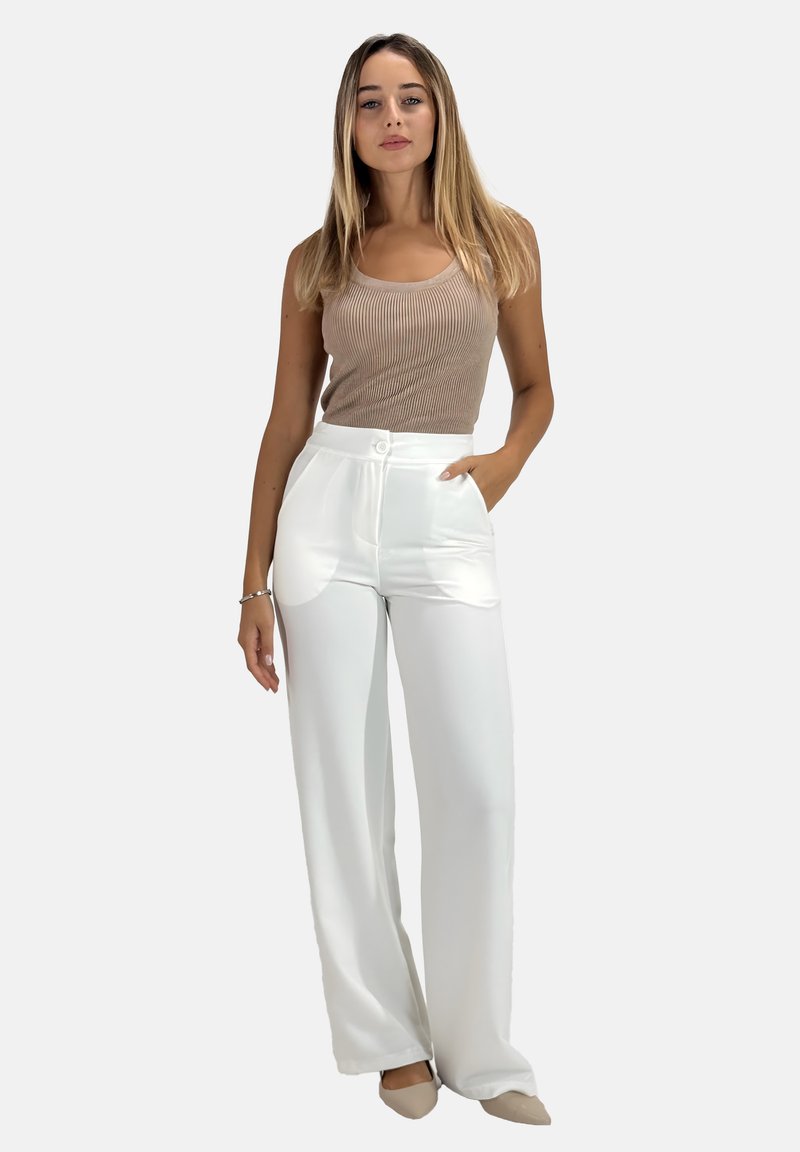 Pantalons blancs à jambes larges avec une texture lisse, dotés de poches avant et d'une fermeture à bouton central, associés à un débardeur beige à côtes.