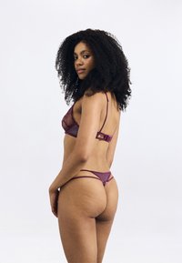 Paarse netstof lingerie set met een geometrisch ontwerp en dunne bandjes. De beha heeft een gedetailleerde voorkant en de string bevat minimale hardwareaccenten.
