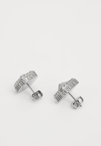 Orecchini a bottone in argento con un design circolare testurizzato e marchiatura incisa, con un piccolo dettaglio a forma di corona sulla parte superiore.