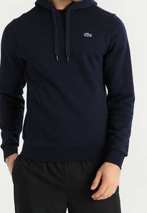 Marineblauer Hoodie aus weichem Stoff mit Kängurutasche, Kordelzug an der Kapuze und besticktem Logo auf der Brust. Schlichtes, figurbetontes Design.