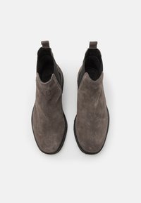 Botas Chelsea de ante gris con paneles laterales elásticos, punta redonda y suela texturizada. Con un práctico tirador en la parte posterior para facilitara su puesta.