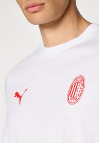 Hvid bomulds t-shirt med rødt Puma-logo og AC Milan-vest. Enkel rund hals, korte ærmer, med glat tekstur og tætsiddende design.