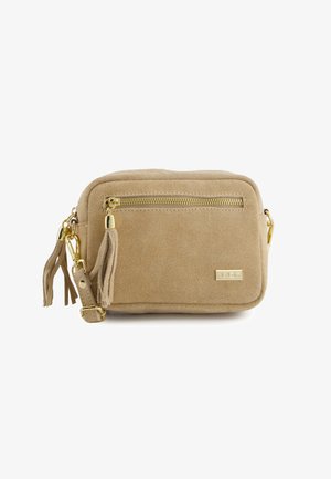 Sac bandoulière rectangulaire en daim beige avec fermeture éclair dorée, tirette pompon, sangle réglable et petite plaque logo métallique.