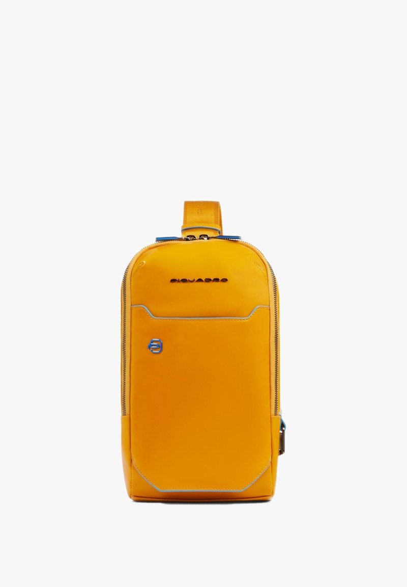 Gele leren rugzak met een gladde textuur, afgeronde vorm, blauwe accenten, een rits aan de voorkant en een bovenhandgreep om te dragen.