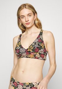 Bralette floral com um decote V profundo, alças largas, e uma mistura de margaridas coloridas sobre um fundo preto, feito de um tecido suave.