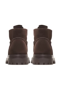 Botine maro până la glezna, din suede moale, cu o textură netedă, vârf rotund și o talpă din cauciuc rugos, cu un model de derapaj pronunțat.