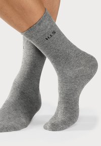 Graue Baumwoll-Crew-Socken mit geripptem Bündchen und schwarzem "H.I.S"-Logo. Der Stoff wirkt glatt und hat eine mittlere Dicke.