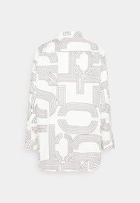 Chemise à manches longues en tissu blanc avec motif géométrique linéaire noir. Présente un col à revers et des poignets boutonnés.
