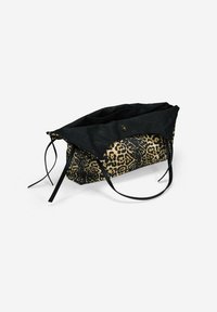 Bolsa de tela con estampado de leopardo, con una parte superior de lona negra y asas largas, que cuenta con un cierre a presión y texturas contrastantes.