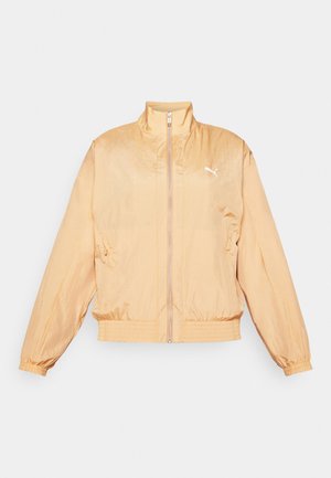 Chaqueta ligera de color melocotón con cuello alto, cremallera frontal, puños elásticos y dobladillo ajustado. Presenta un logo blanco en el lado izquierdo del pecho.